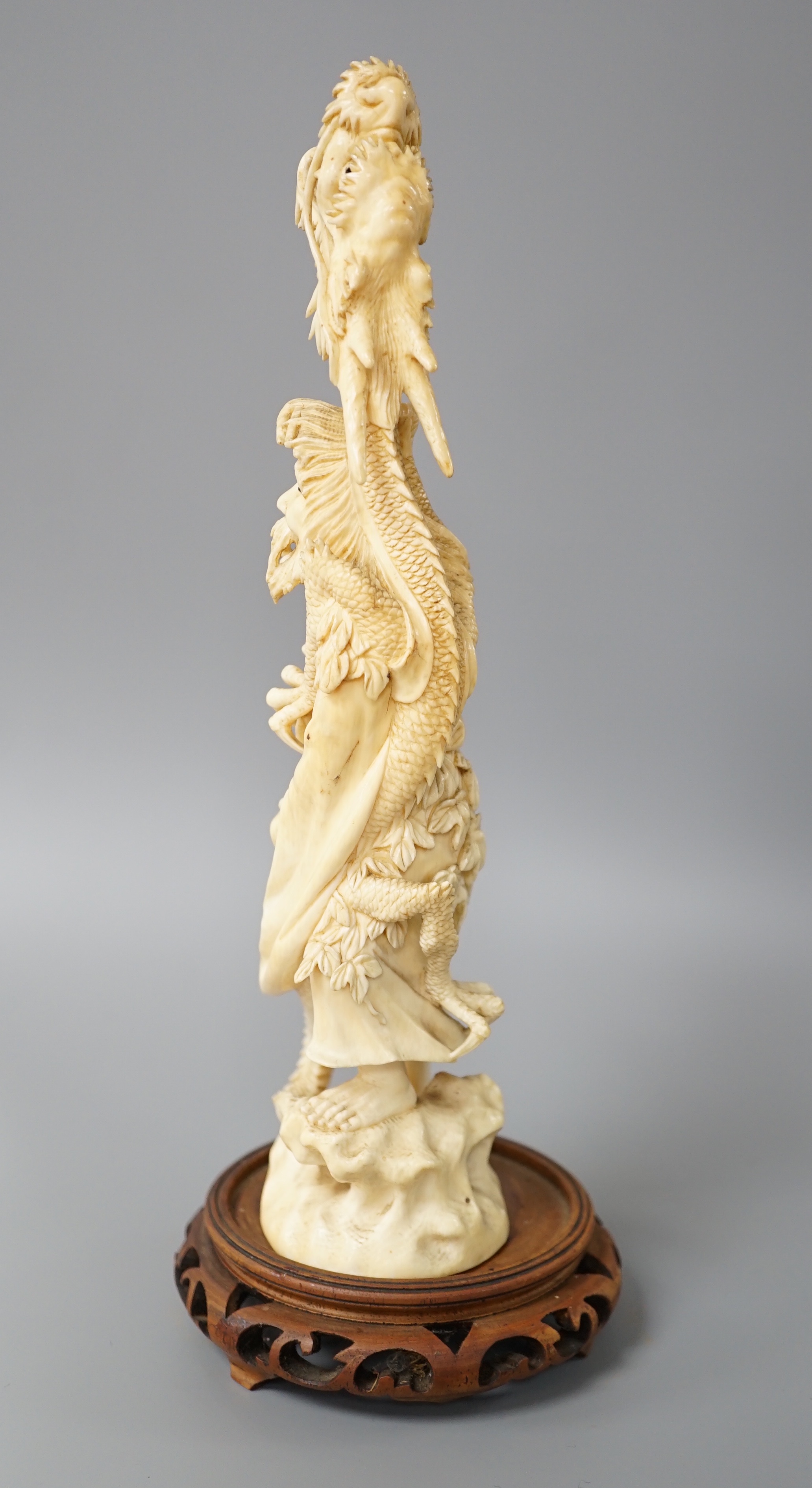 A Japanese ivory okimono of Shoshi Sennin and a dragon, early 20th century, signed, associated wood stand, 24cm excl stand